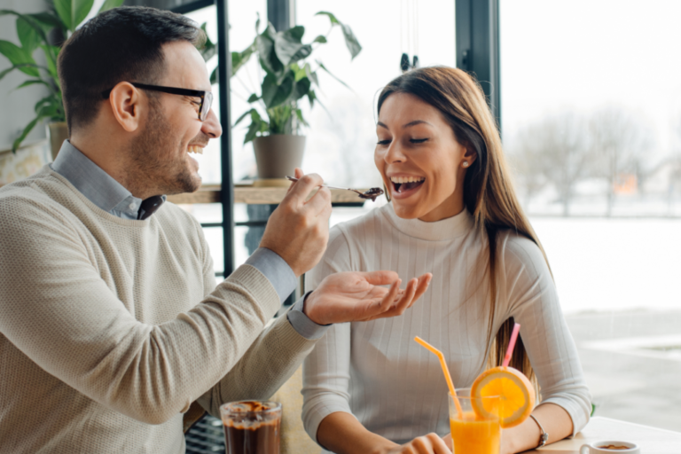 couple feeding each other cake at cafe