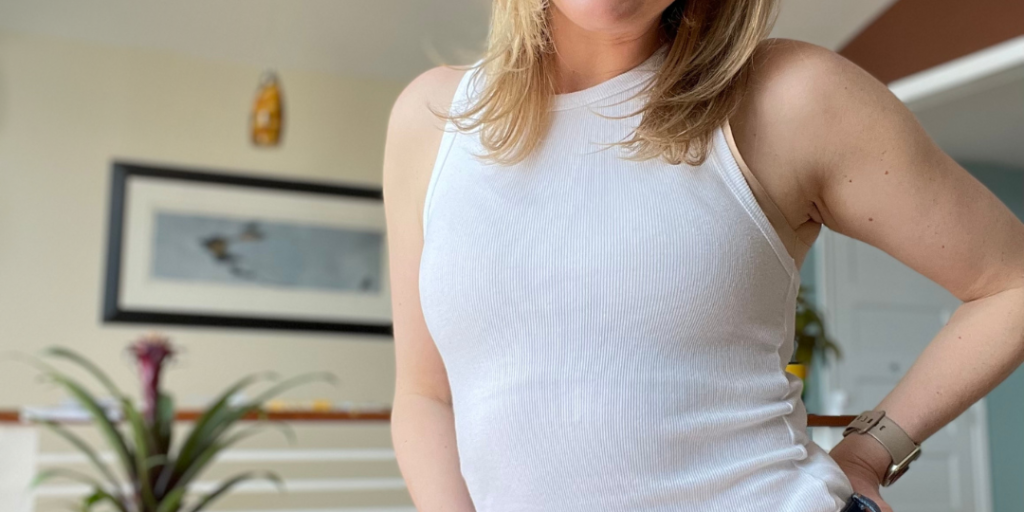 woman with blonde hair standing with a big smile and has her hand on her hip