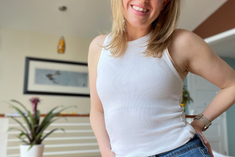 woman with blonde hair standing with a big smile and has her hand on her hip
