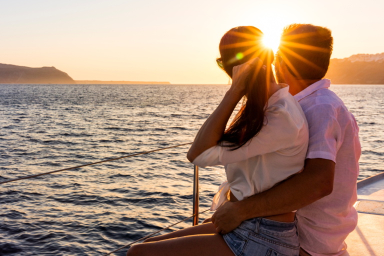 Couple cuddling on boat look into the sunset