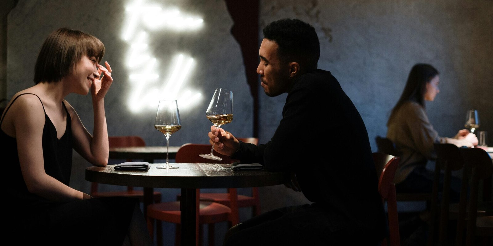 Couple enjoying a romantic evening with white wine in a stylish bar setting.