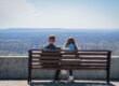 A couple sitting on a bench, a quiet distance between them.