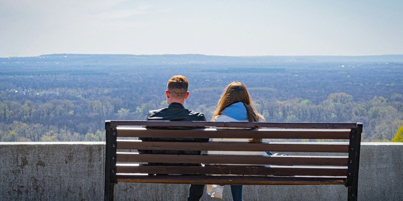 attracting-unavailable-couple-bench A couple sitting on a bench, a quiet distance between them.