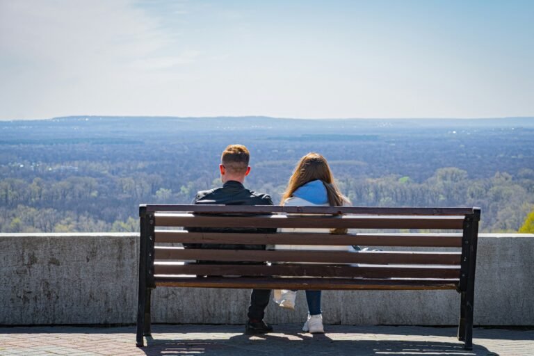A couple sitting on a bench, a quiet distance between them.