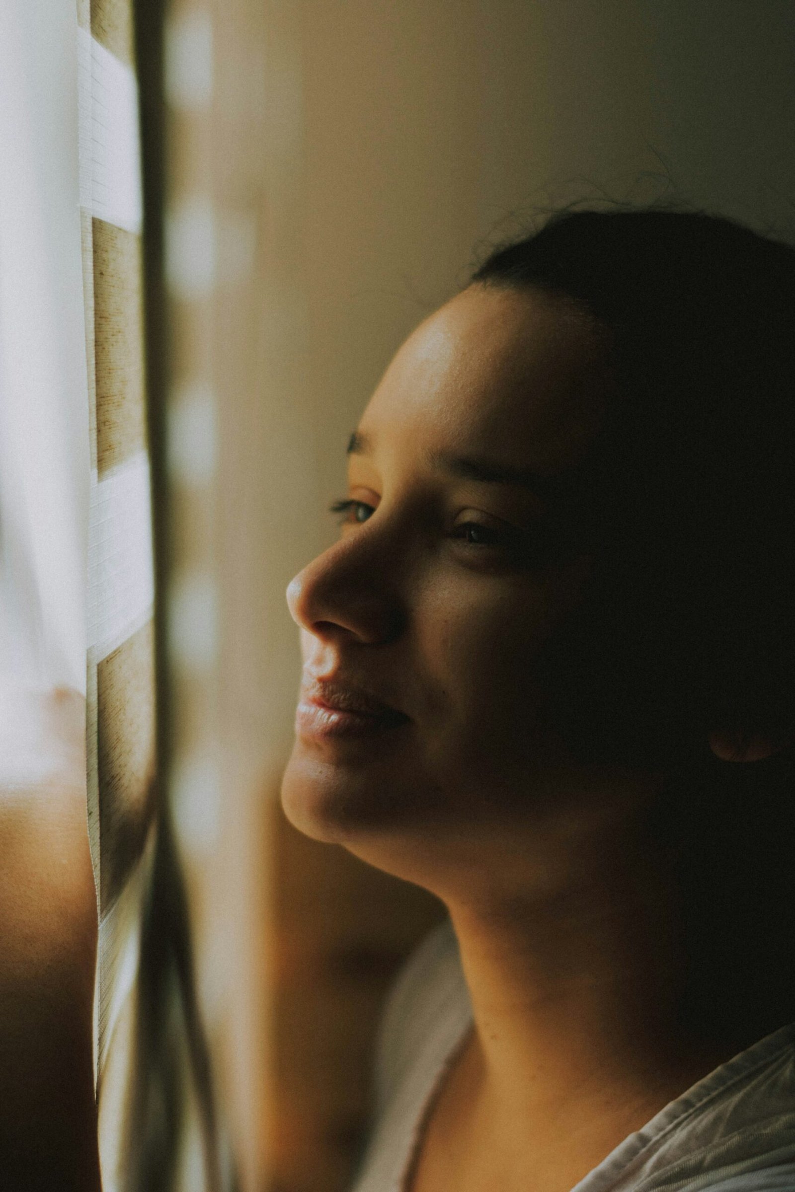 A woman smiling softly in warm indoor light.
