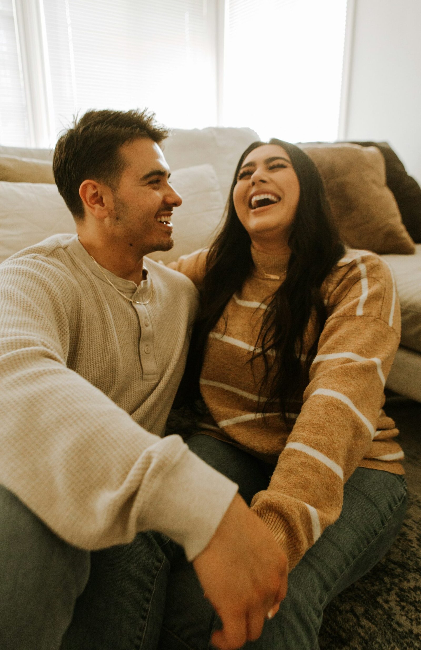 A couple laughing together, relaxed and at ease.