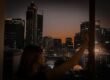 A person looking out at the city lights at night, alone.