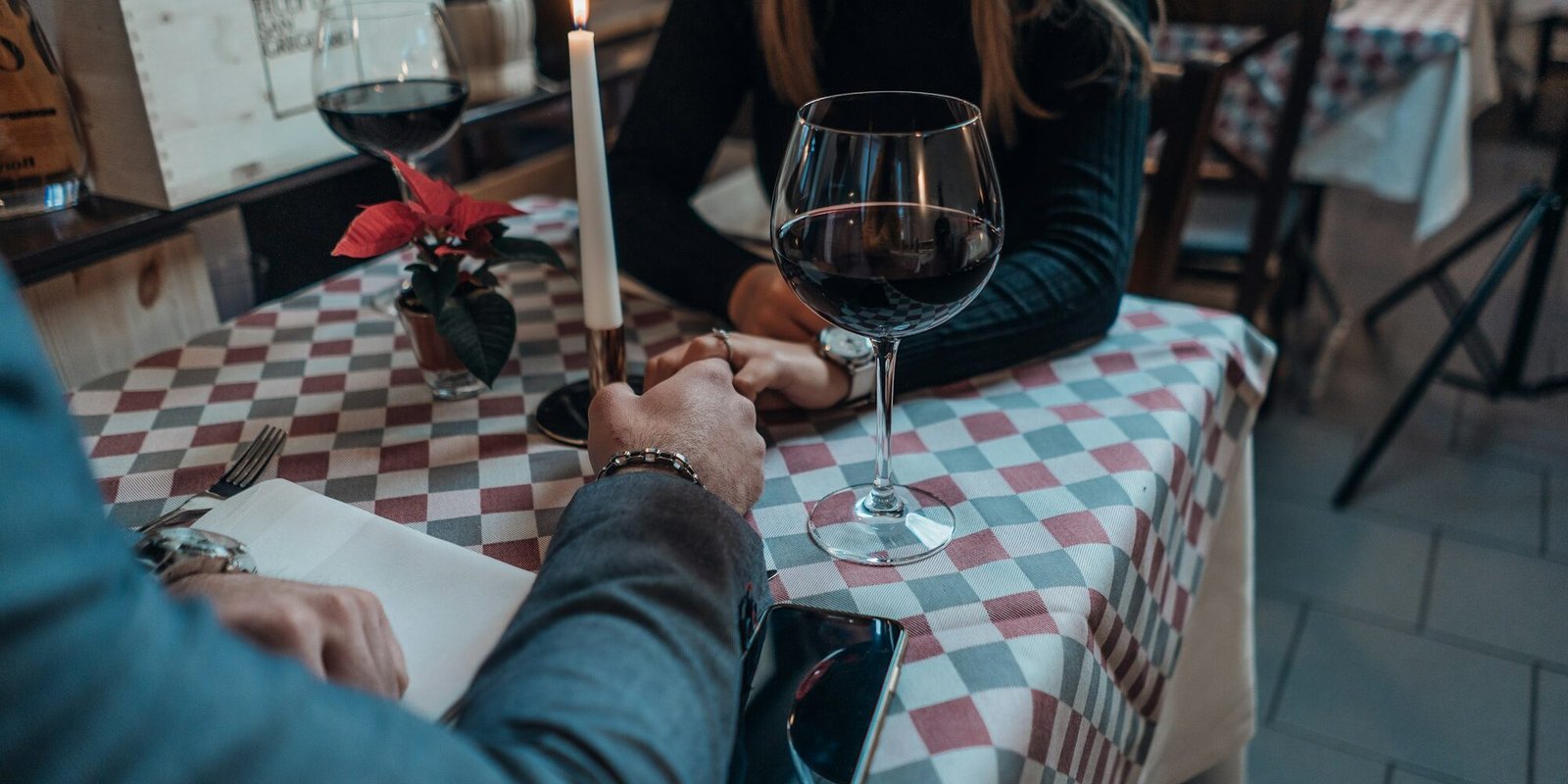 An elegant couple holding hands across a table in warm light.