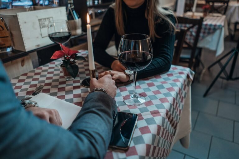 An elegant couple holding hands across a table in warm light.