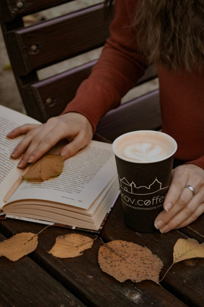 A woman reading with a cup of coffee, cozy and unhurried.