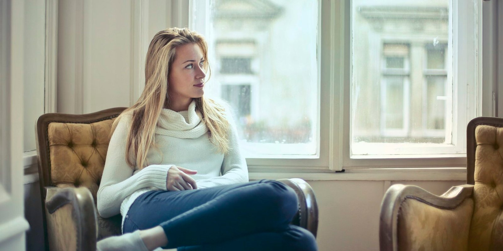 A woman sitting alone in an armchair, lost in thought.