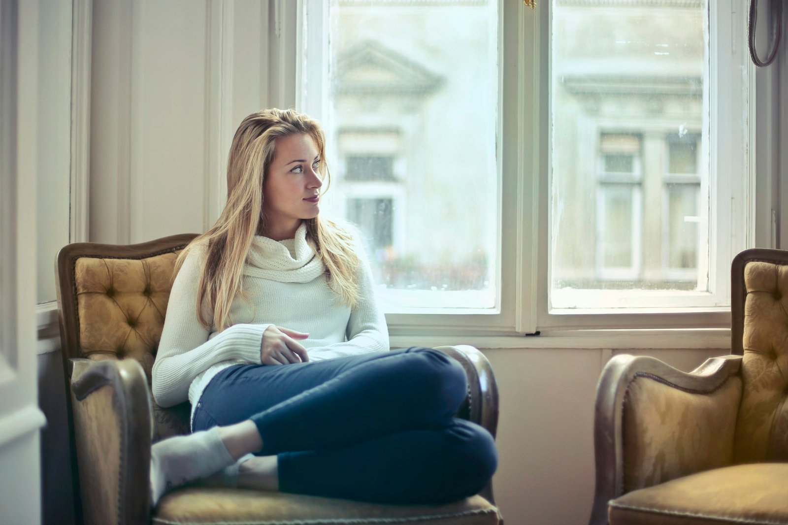 A woman sitting alone in an armchair, lost in thought.