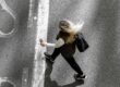 A woman walking alone down a quiet road, seen from behind.