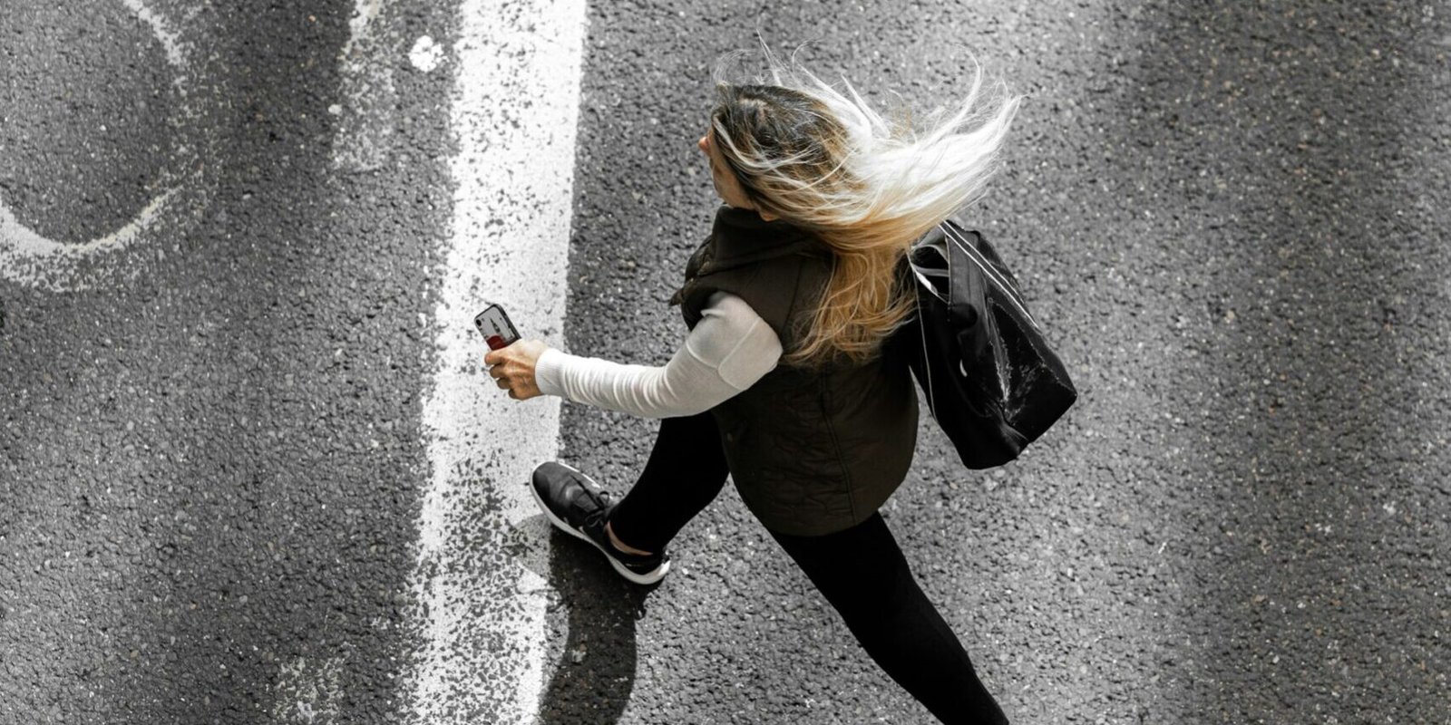 A woman walking alone down a quiet road, seen from behind.