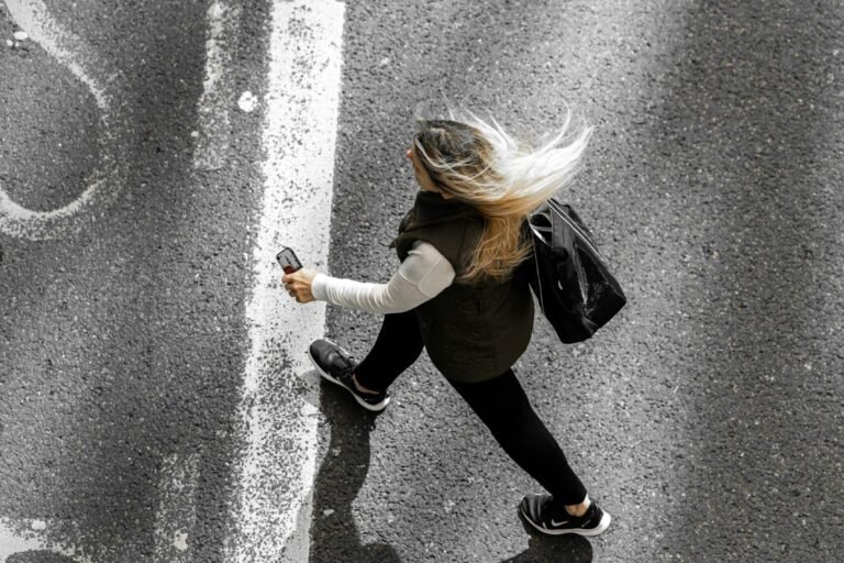 A woman walking alone down a quiet road, seen from behind.