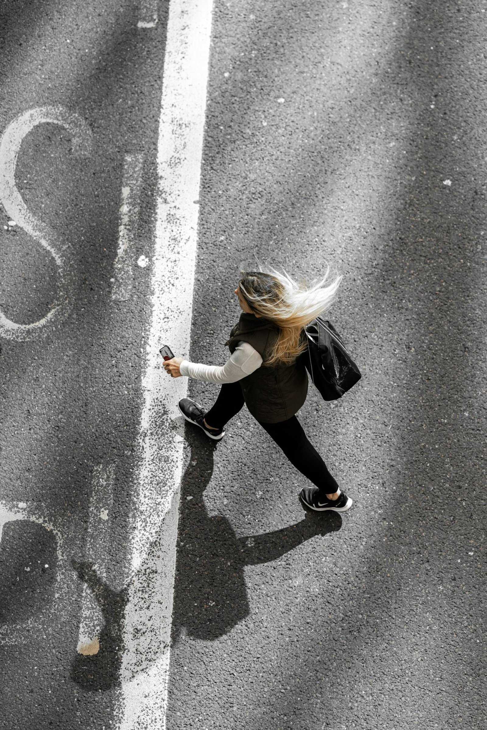 A woman walking alone down a quiet road, seen from behind.