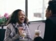 Two people talking and laughing together over coffee.
