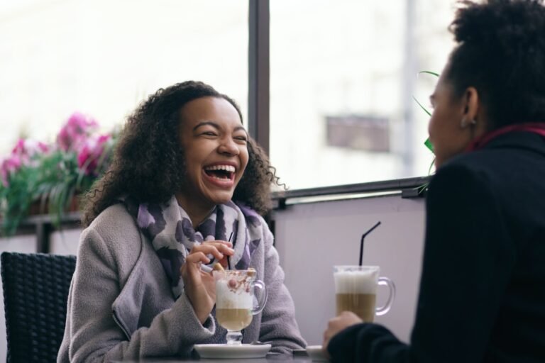 Two people talking and laughing together over coffee.