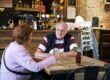 A couple talking across a small cafe table.