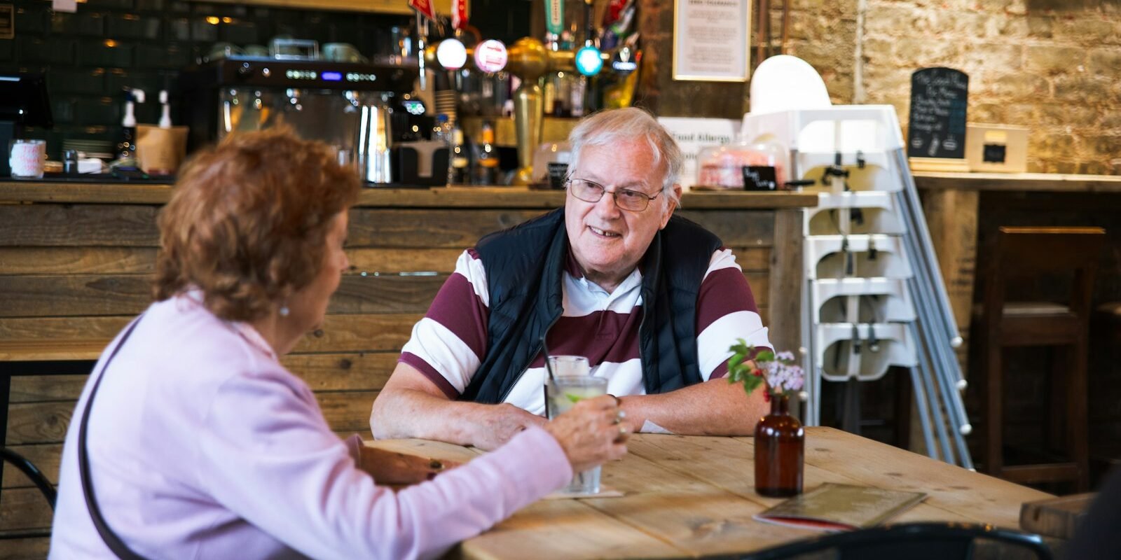 A couple talking across a small cafe table.
