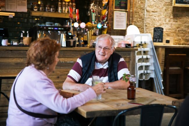 A couple talking across a small cafe table.