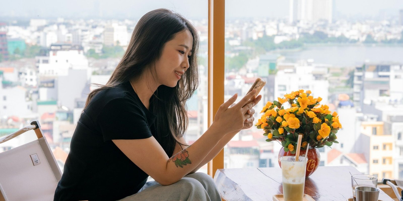 how-much-text-between-dates-phone-window A person holding a phone by a bright window in soft daylight.
