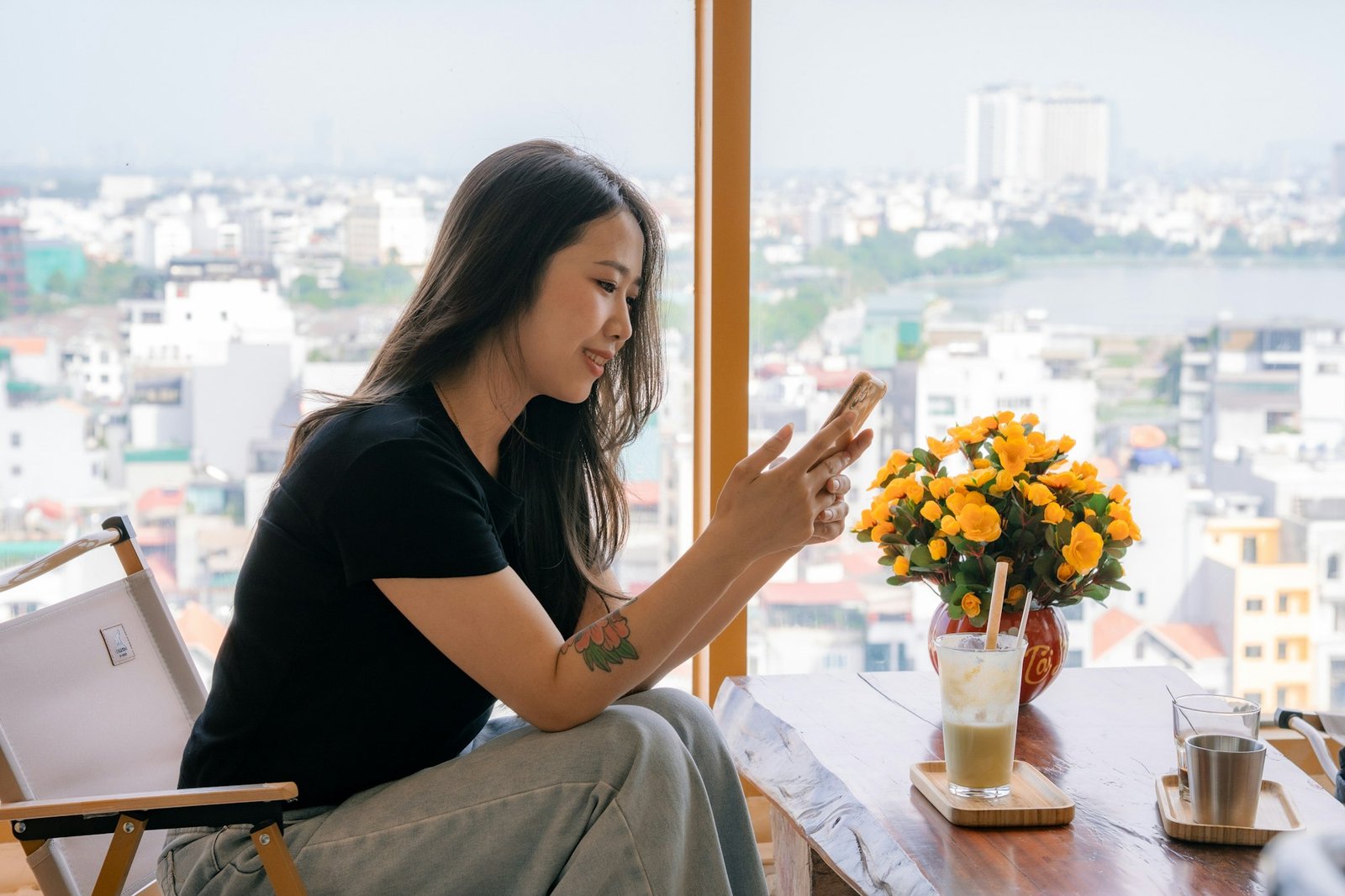 A person holding a phone by a bright window in soft daylight.