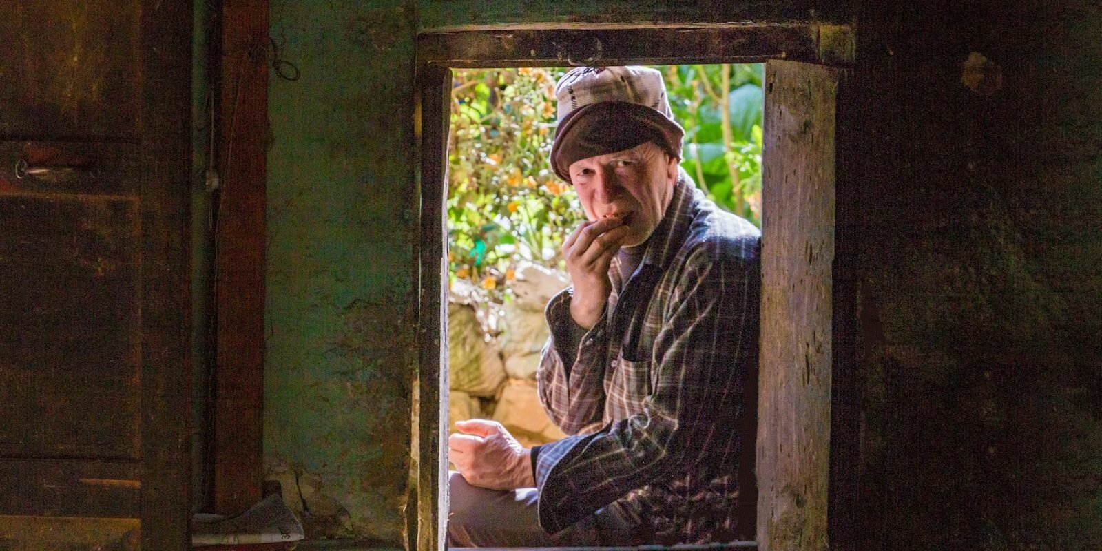 An older man by a window, quiet and thoughtful.