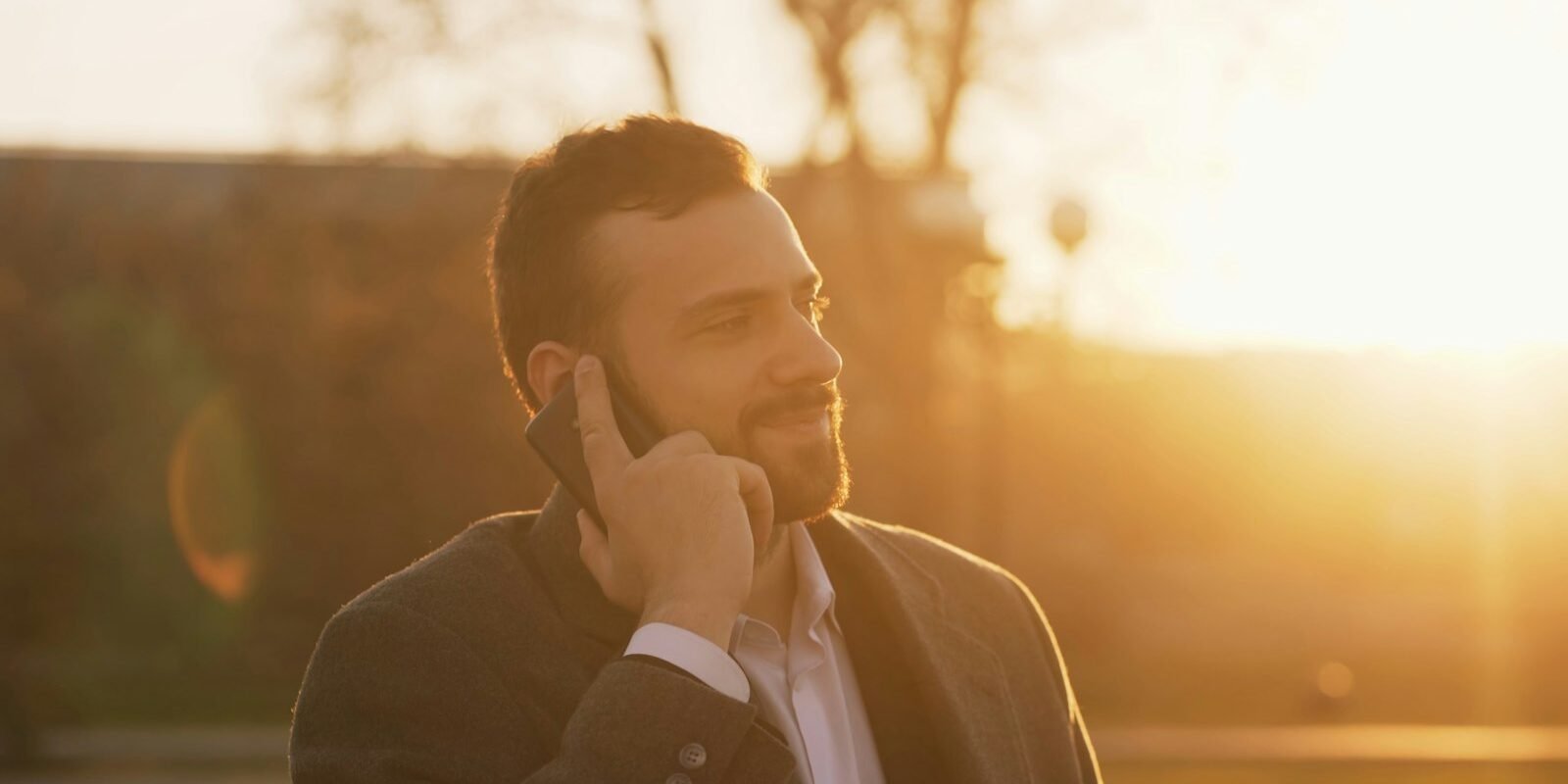 A well-dressed man in a suit looking at his phone.