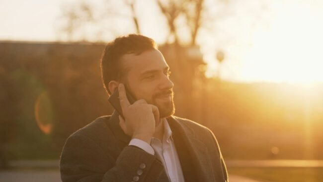A well-dressed man in a suit looking at his phone.