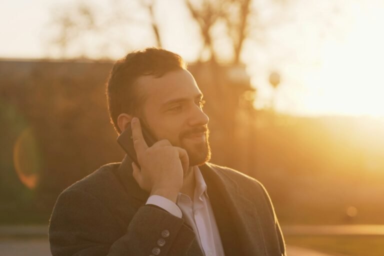 A well-dressed man in a suit looking at his phone.